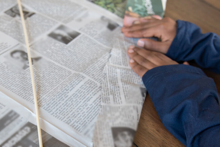 男孩将报纸折叠在风筝的棍架上。