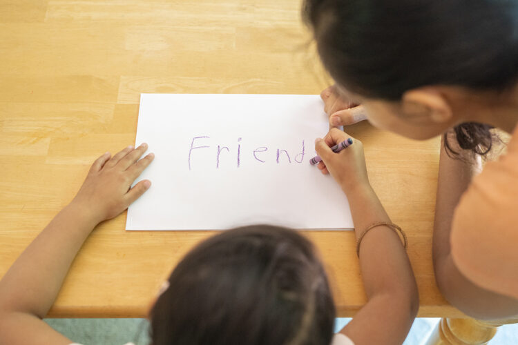 一个孩子在她的书的封面上写下“朋友”。