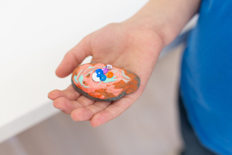 男孩拿着彩绘和装饰的岩石。