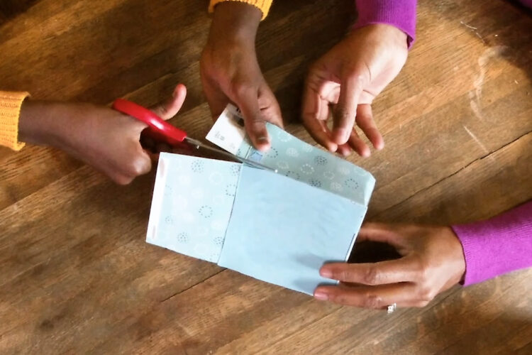 一对母女将纸巾盒底部的边缘切开，制成一个可以提起的翻盖。