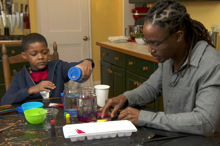 一个儿子将闪光粉混入一杯水中。