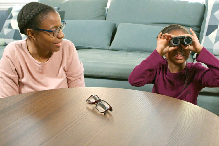 在放大镜活动中，母女俩一起看双筒望远镜。