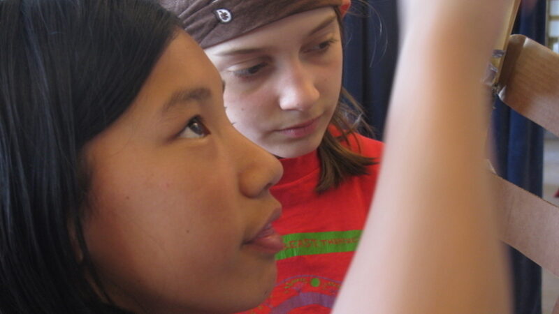 两个女孩看着她们正在建造的东西的特写。