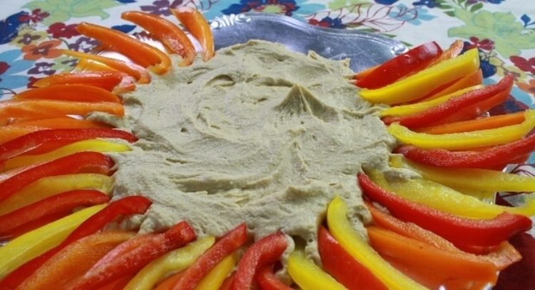 将切成片的红色、黄色和橙色甜椒放在鹰嘴豆泥的边缘，形成“鬃毛”。